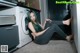 A woman sitting on the floor in front of a washing machine.