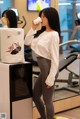 A woman standing in front of a mirror drinking from a cup.