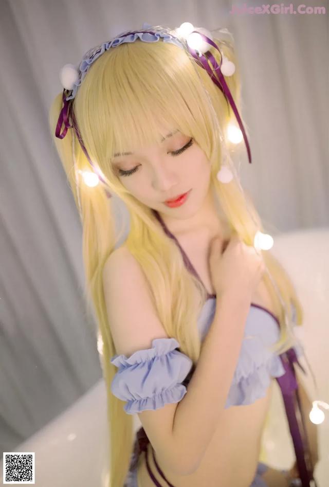 A woman with long blonde hair wearing a purple outfit.