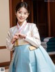 A woman in a blue and white hanbok poses for a picture.