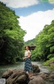 A woman standing on a rock in the middle of a river.