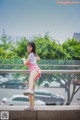 A woman in a pink skirt is standing on a railing.