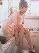 A woman sitting on a kitchen counter with her legs crossed.