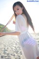 A woman in a white dress standing on a beach.