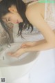 A woman in a white lingerie washing her hands in a sink.