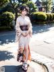 A woman in a kimono standing on a sidewalk.