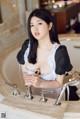 A woman in a maid outfit sitting in a bathtub.