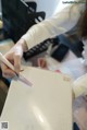 A woman is writing on a piece of paper with a pencil.