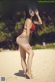 A woman in a red bikini standing on a beach.