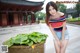 A woman standing next to a potted plant in front of a building.