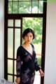 A woman in a black dress standing in front of a window.