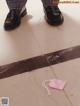 A person standing on a tiled floor next to a pink tag.