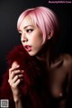 A woman with pink hair wearing a fur coat.