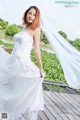 A woman in a wedding dress standing on a wooden bridge.