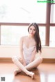 A woman sitting on the floor in a white lingerie.