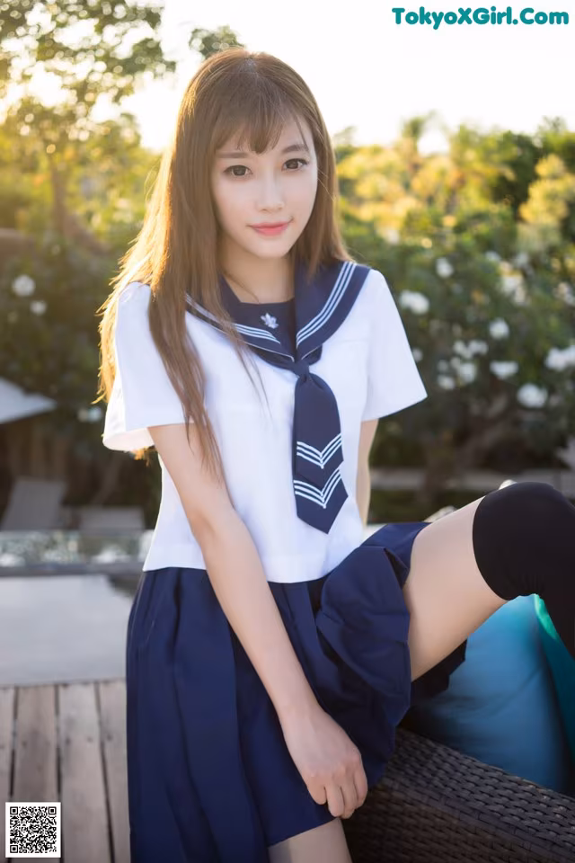 A woman in a sailor outfit sitting on a chair.