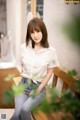 A woman sitting on a wooden bench wearing a white shirt.