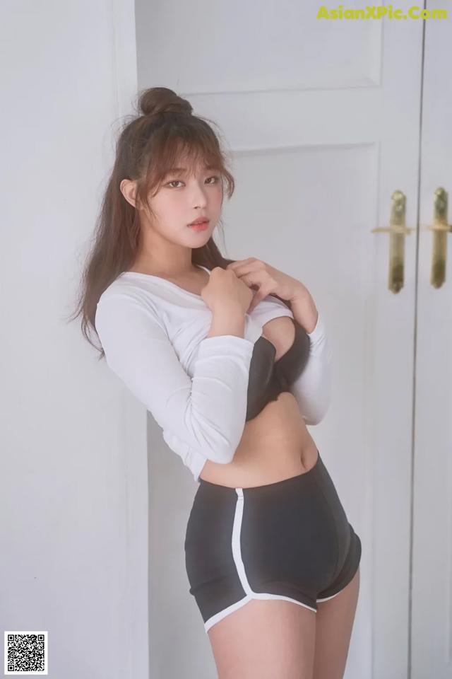 A woman in a white shirt and black shorts posing for a picture.