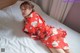 A woman in a red kimono laying on a bed.