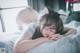 A woman laying on a bed wearing cat ears and glasses.