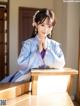 A woman in a blue hanbok sitting on a wooden bench.